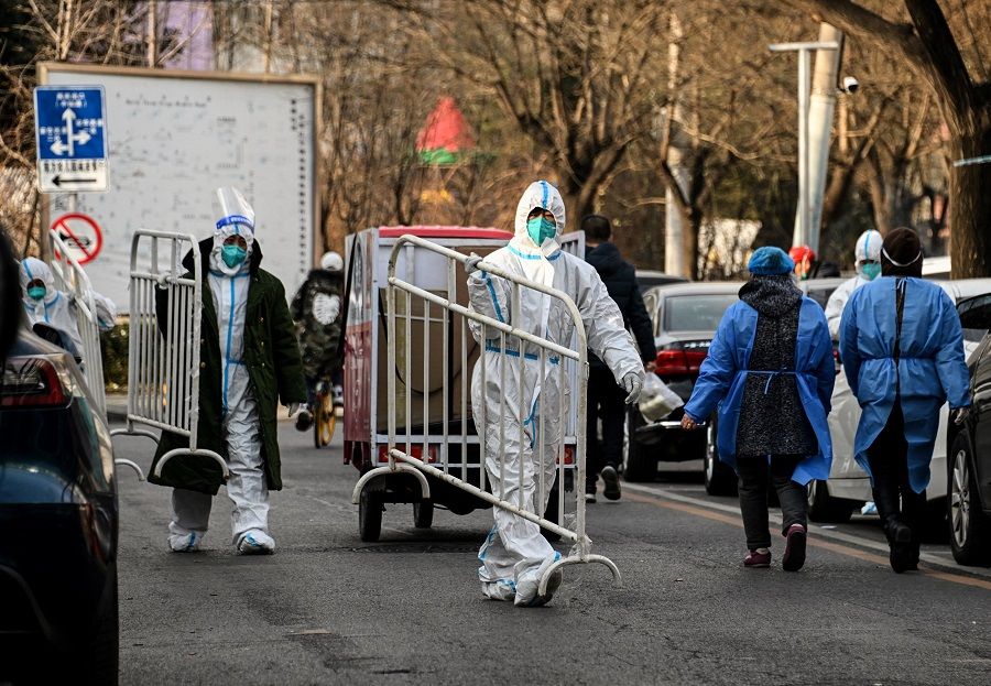 Health workers wearing personal protective equipment (PPE) carry barricades inside a residential community that just opened after a lockdown due to Covid-19 restrictions in Beijing, China, on 9 December 2022. (Noel Celis/AFP)