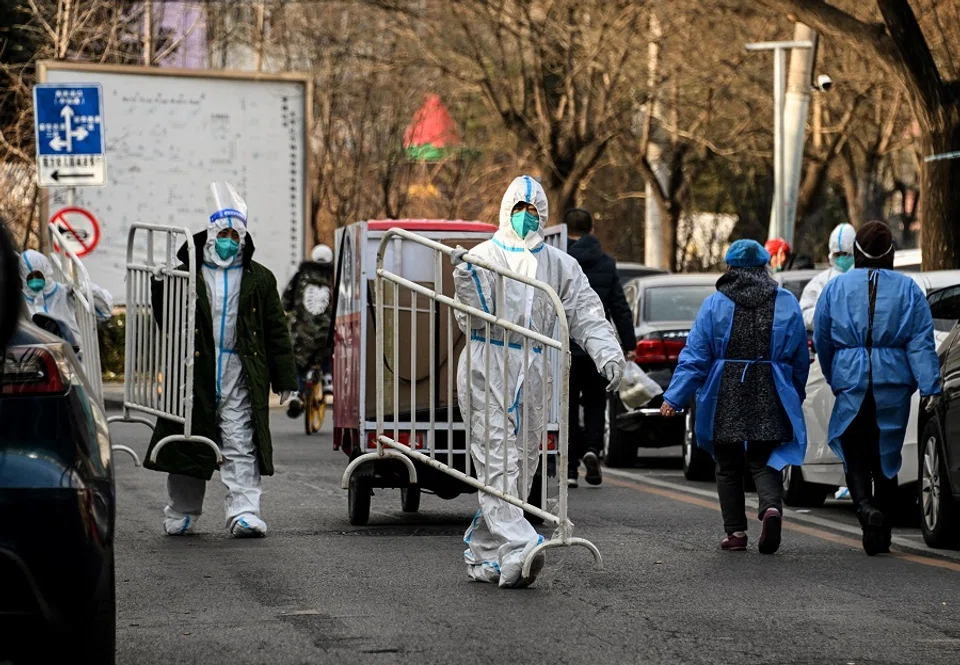 Health workers wearing personal protective equipment (PPE) carry barricades inside a residential community that just opened after a lockdown due to Covid-19 restrictions in Beijing, China, on 9 December 2022. (Noel Celis/AFP)