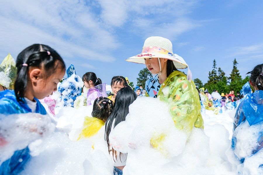 This photo taken on 3 May 2022 shows children playing with bubbles at a park in Qianxinan, Guizhou province, China. (AFP)