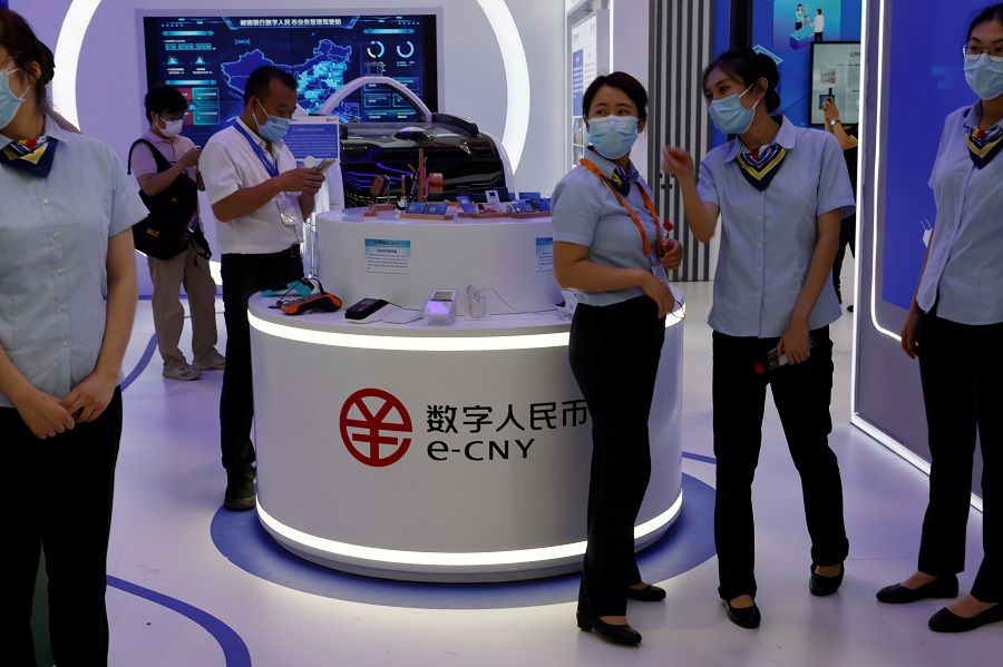 Staff members stand near a counter promoting China's digital yuan, or e-CNY, at the 2021 China International Fair for Trade in Services (CIFTIS) in Beijing, China, 3 September 2021. (Florence Lo/Reuters)