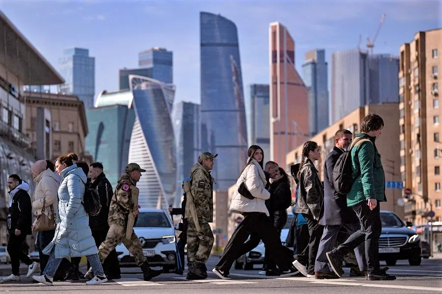 People cross a street in front of the Moscow International Business Centre in Moscow, Russia, on 28 March 2023. (Natalia Kolesnikova/AFP)