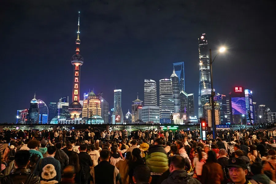 People cross a street on the Bund in Shanghai, China, on 13 February 2024. (Hector Retamal/AFP)