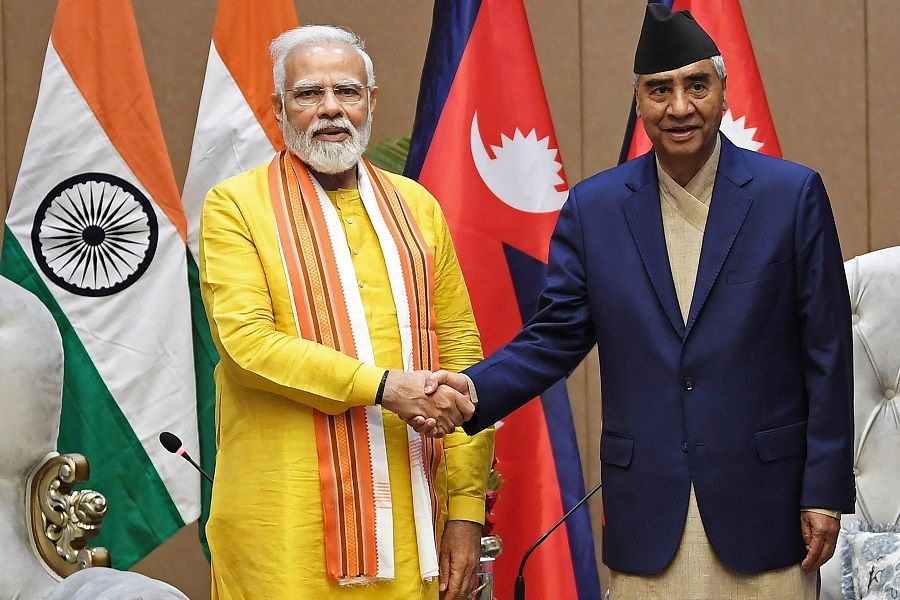 This handout photograph taken on 16 May 2022 and released by the Indian Press Information Bureau (PIB) shows India's Prime Minister Narendra Modi (left) shaking hands with his Nepali counterpart Sher Bahadur Deuba before their meeting in Lumbini, Nepal. (Indian Press Information Bureau/AFP)
