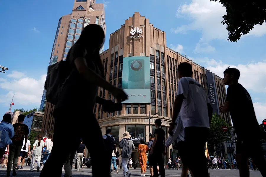 Pedestrians walk past an advertisement for Huawei's Mate 60 series smartphones outside a Huawei store in Shanghai, China, 8 September 2023. (Aly Song/Reuters)