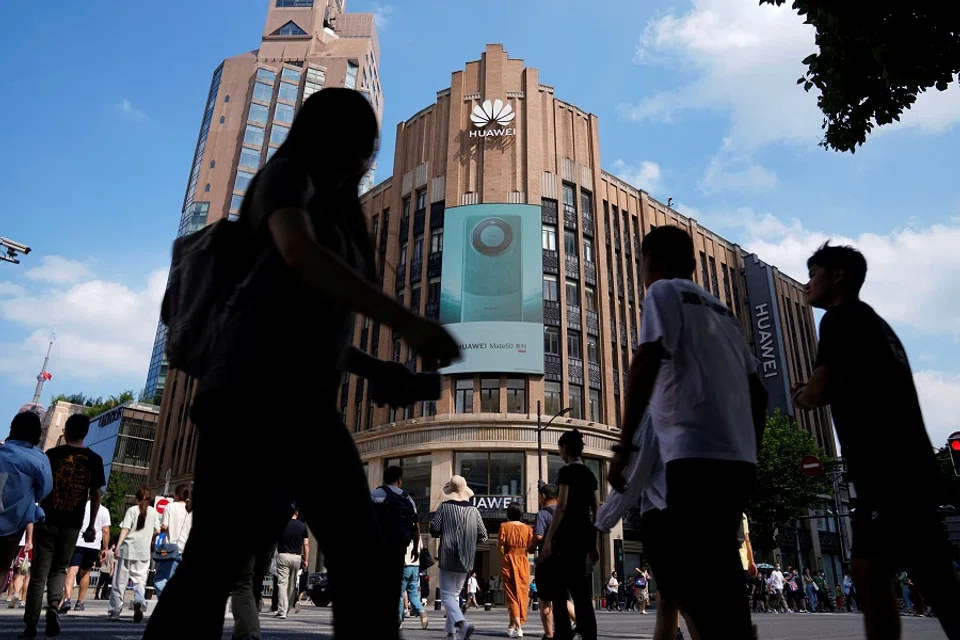 Pedestrians walk past an advertisement for Huawei's Mate 60 series smartphones outside a Huawei store in Shanghai, China, 8 September 2023. (Aly Song/Reuters)