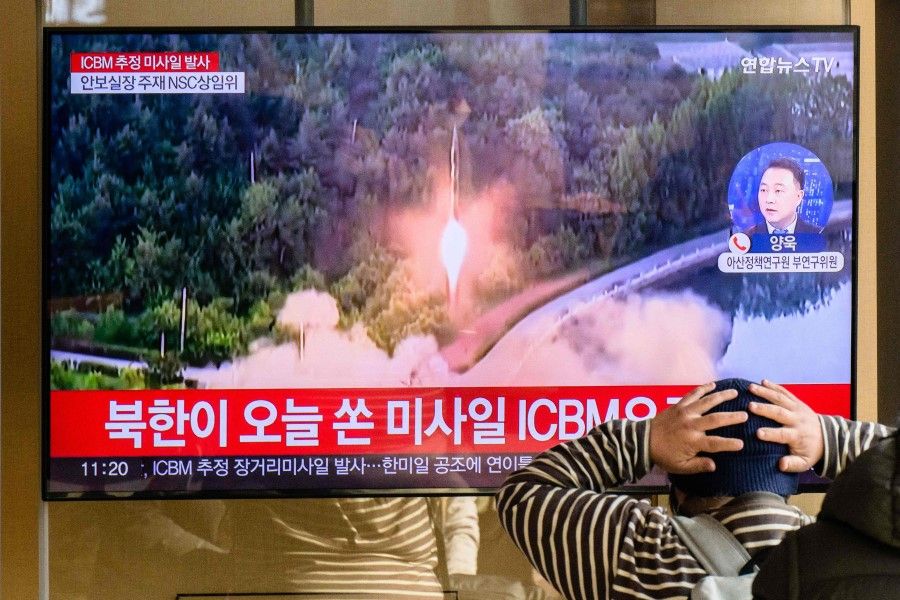A man watches a television showing a news broadcast with file footage of a North Korean missile test, at a railway station in Seoul on 18 November 2022. (Anthony Wallace/AFP)