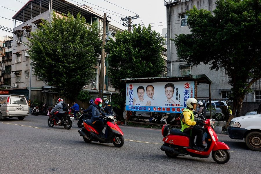 People ride pass a campaign ad for Hou Yu-ih, the presidential candidate of the main opposition party Kuomintang (KMT), ahead of the election in Taipei, Taiwan, on 12 January 2024. (Ann Wang/Reuters)