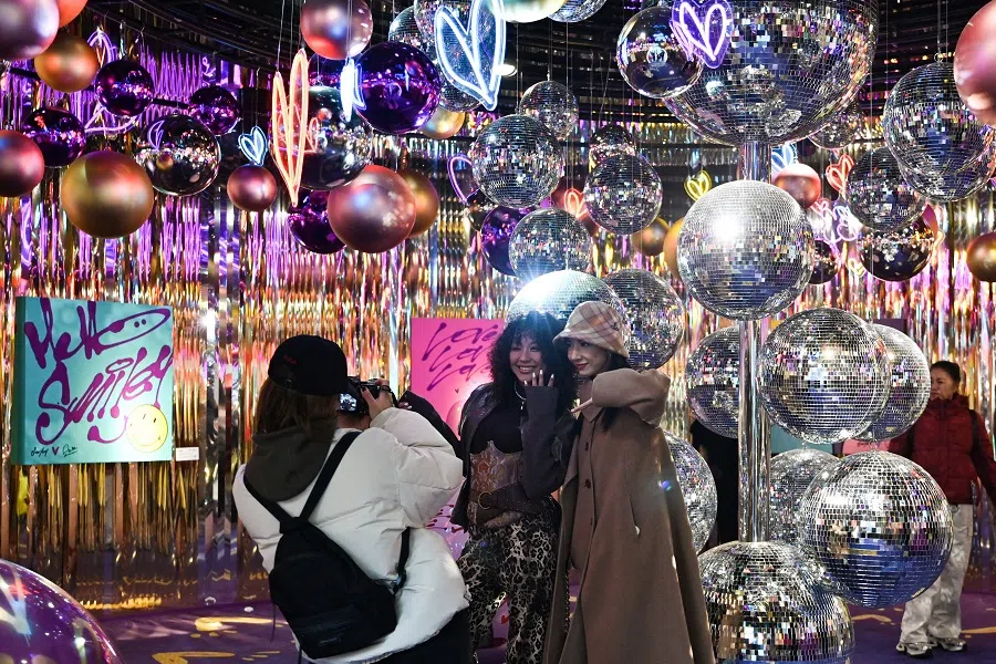 People pose for photos at an installation outside a shopping centre in Beijing, China, on 24 December 2024. (Adek Berry/AFP)