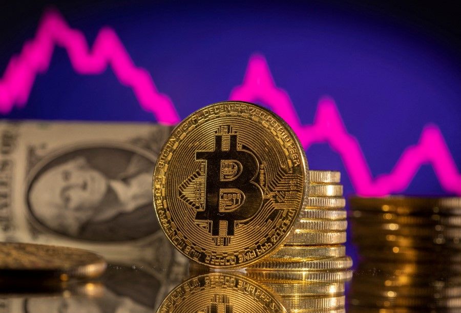 A representation of cryptocurrency Bitcoin is seen in front of a stock graph and US dollar in this illustration taken 24 January 2022. (Dado Ruvic/Reuters)