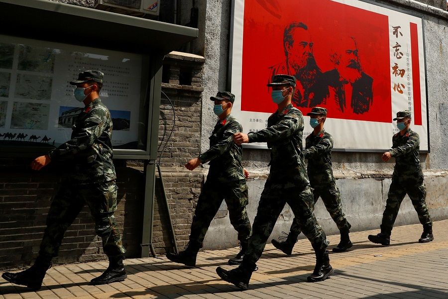 Chinese servicemen walk past portraits of philosophers Karl Marx and Friedrich Engels with the caption "Remain True to our Original Aspiration" (不忘初心) and patrol a street near the Great Hall of the People on the opening day of the National People's Congress, in Beijing, China, on 22 May 2020. (Thomas Peter/Reuters)