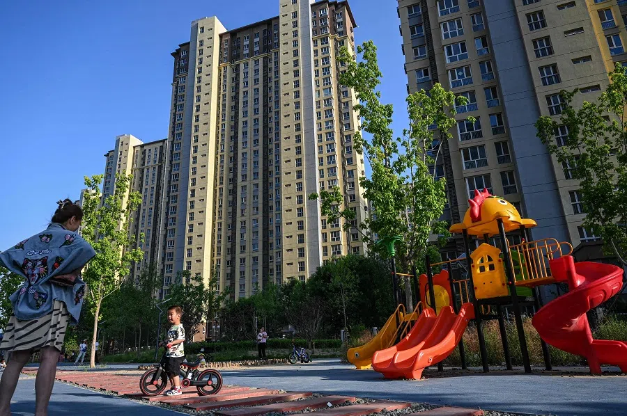 A woman watches her child at a playground of a residential compound in Beijing, China, on 17 May 2024. (Jade Gao/AFP)