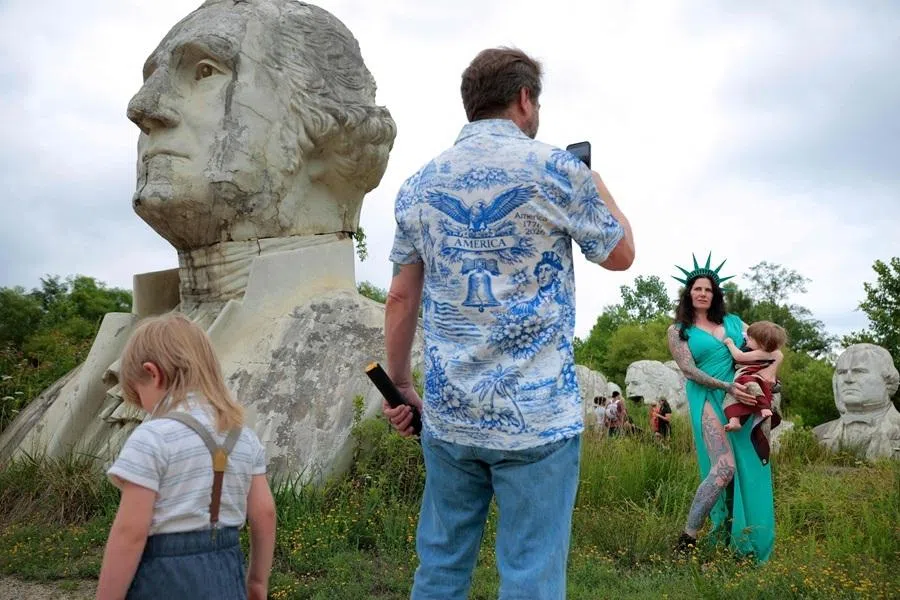 Visitors get a photograph next to the giant, crumbling concrete bust of former US President George Washington at The Presidents Heads on 27 June 2026 in Williamsburg, Virginia.