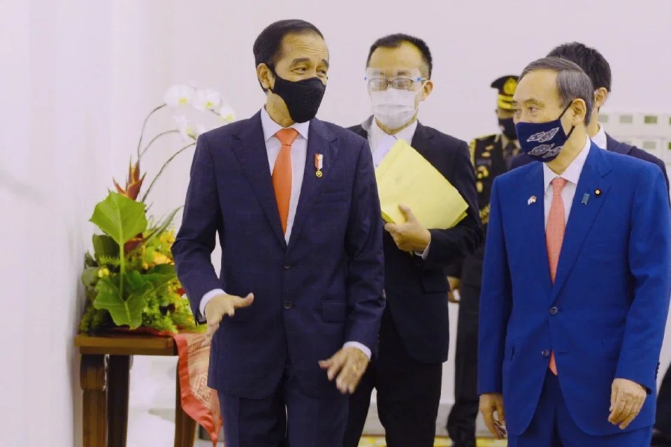 This handout photo taken and released on 20 October 2020 by the Indonesian Presidential Palace shows Japan's Prime Minister Yoshihide Suga (R) and Indonesian President Joko Widodo (L) walking during a welcoming ceremony at the presidensial palace in Bogor on the outskirts of Jakarta. (Handout/Indonesian Presidential Palace/AFP)