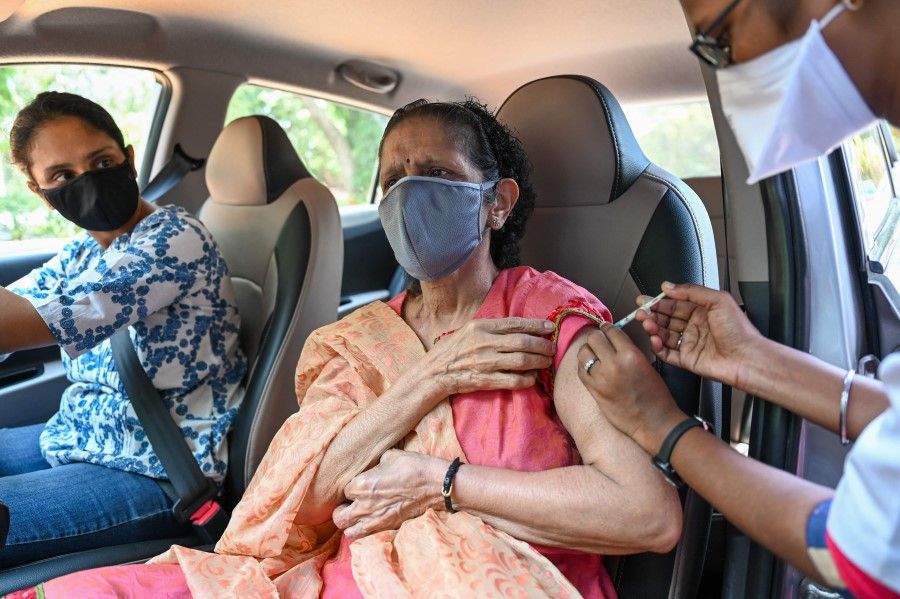 An elderly woman gets inoculated with a dose of the Covishield vaccine against the Covid-19 coronavirus at a drive-in vaccination facility in Mumbai on 11 May 2021. (Punit Paranjpe/AFP)