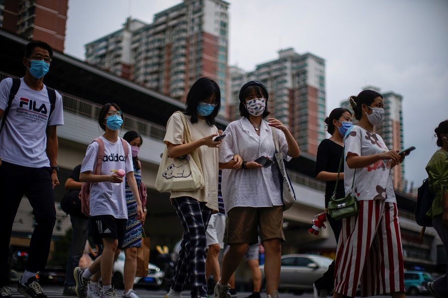 People wearing protective masks walk on a street in Shanghai, China, 10 August 2021. (Aly Song/Reuters)