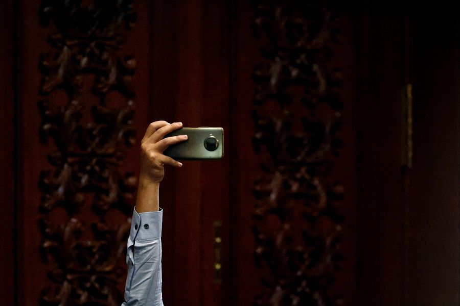 A journalist holds a mobile phone while waiting at the Great Hall of the People for the closing ceremony of the 20th Party Congress of the Communist Party of China in Beijing, China, 22 October 2022. (Tingshu Wang/Reuters)