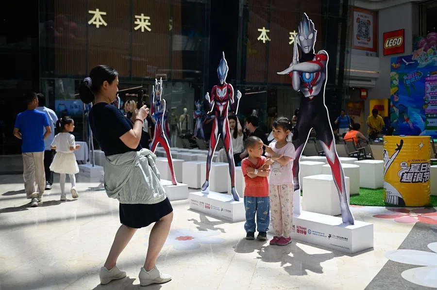 Children pose for a picture in front of the cartoon character Ultraman at a mall in Beijing, China on 1 June 2024. (Wang Zhao/AFP)