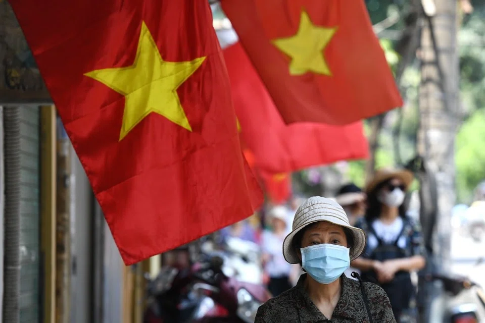 A woman walks past Vietnam national flags along a street in Hanoi, 18 May 2020. (Nhac Nguyen/AFP)