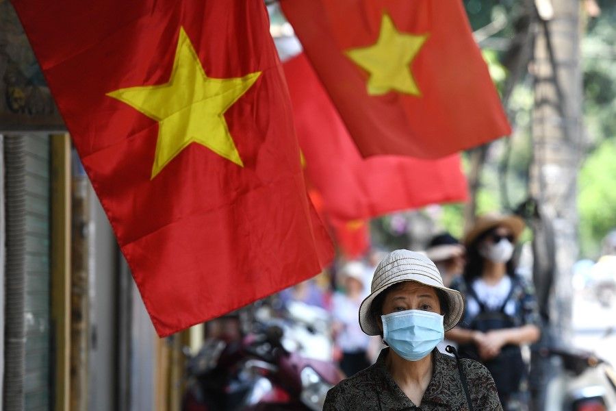 A woman walks past Vietnam national flags along a street in Hanoi, 18 May 2020. (Nhac Nguyen/AFP)