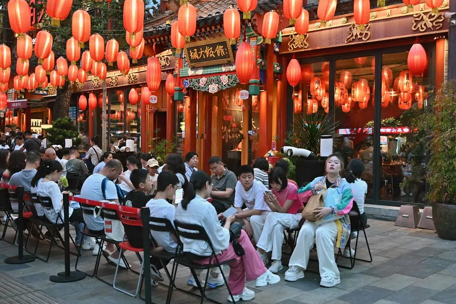 People wait outside under red lanterns for their turn to dine at a restaurant in Beijing on 13 July 2024.  (Adek Berry/AFP)