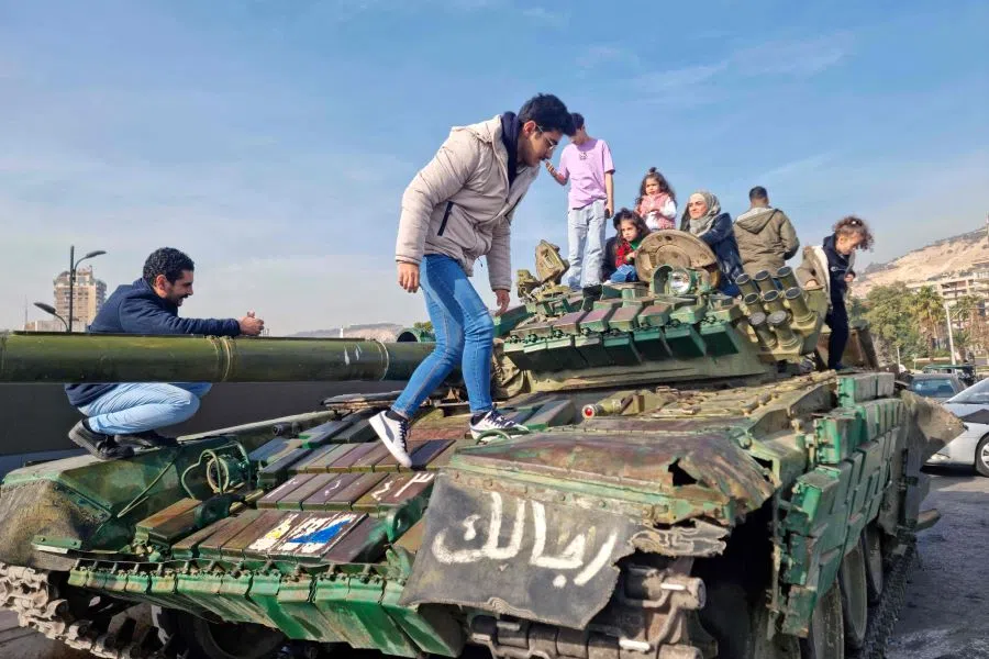 People visit an army tank belonging to the toppled Syrian government, in Damascus on 10 December 2024, after Islamist-led rebels took Damascus in a lightning offensive on 8 December, ousting President Bashar al-Assad and ending five decades of Baath rule in Syria.