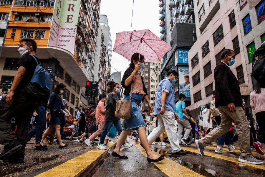 Pedestrians walk on a street in the Wanchai district of Hong Kong on 6 August 2021. (Isaac Lawrence/AFP)