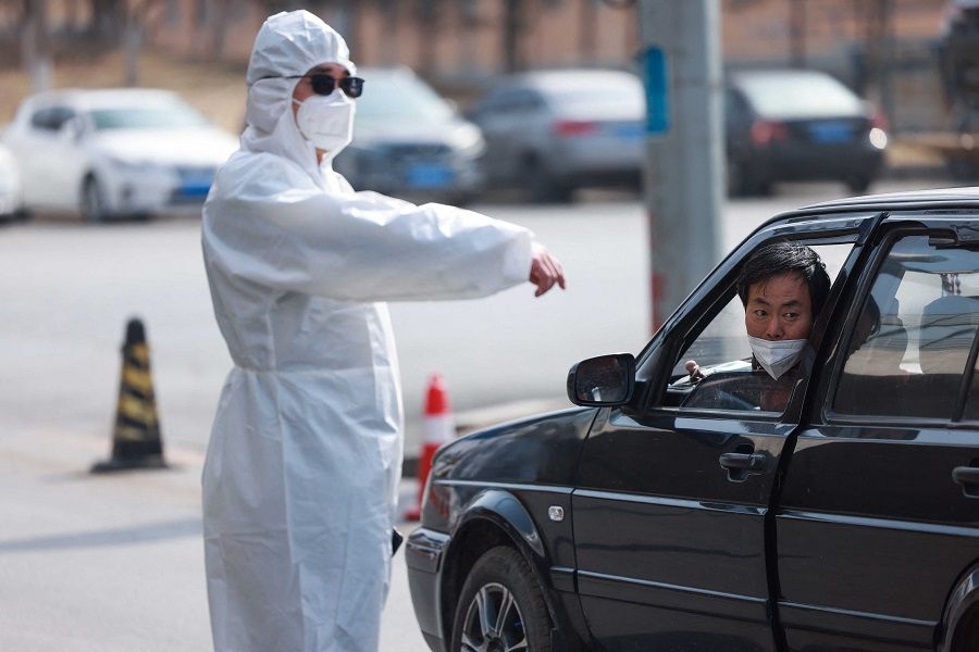 A police officer wearing PPE speaks with a driver at a checkpoint between two districts as authorities restrict the movement of people between districts as a preventive measure against the spread of Covid-19 in Shenyang, Liaoning province, China, on 8 April 2022. (AFP)