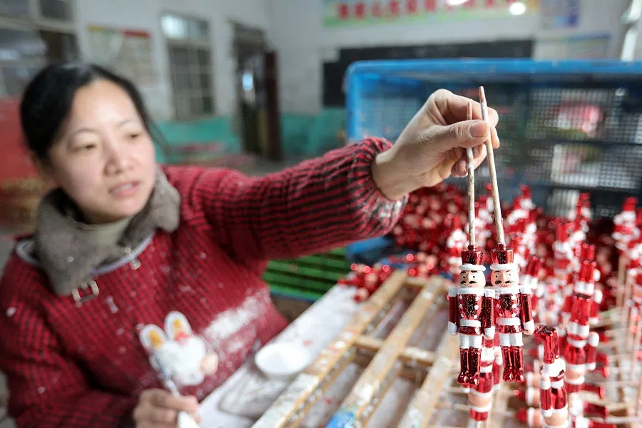 A worker holds up Christmas decorations at a workshop in Huaibei, in China’s eastern Anhui Province on 10 December 2024. (AFP)