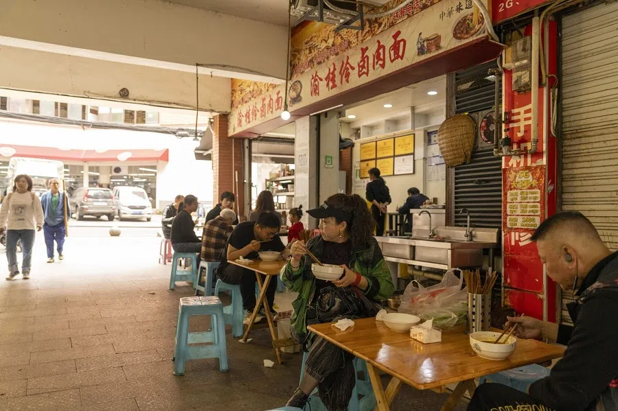Customers eat noodles at a food stall in Chongqing, China, on 2 May 2024.  (Raul Ariano/Bloomberg)