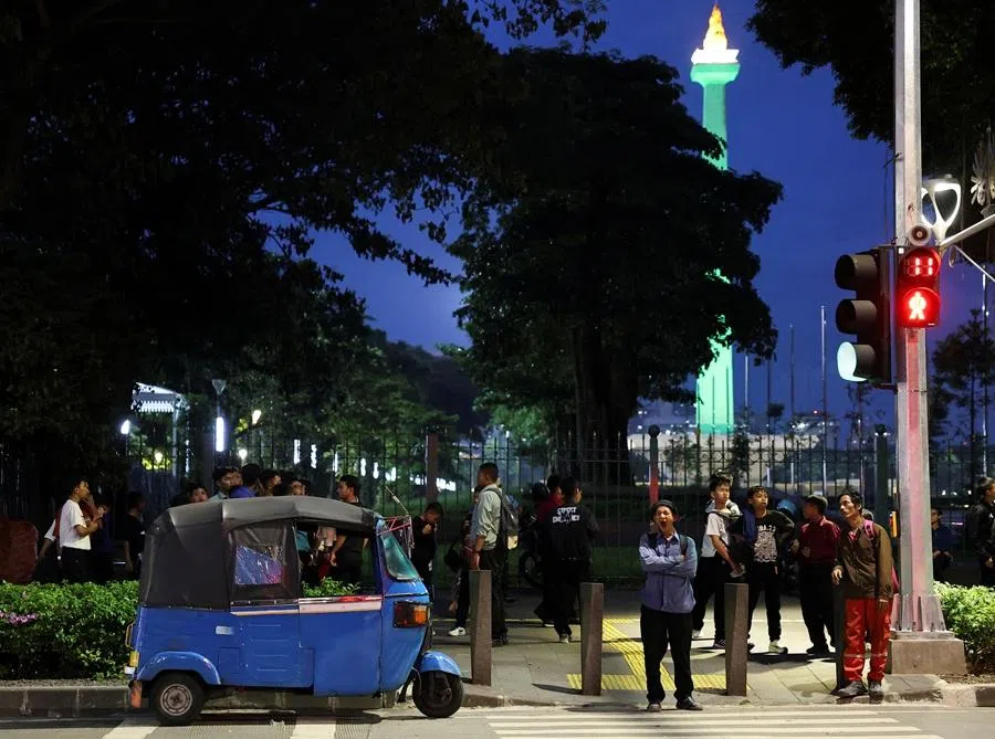 People wait to cross a road outside the National Monument (Monas) complex in Jakarta, Indonesia, 8 January 2026. (Willy Kurniawan/Reuters)