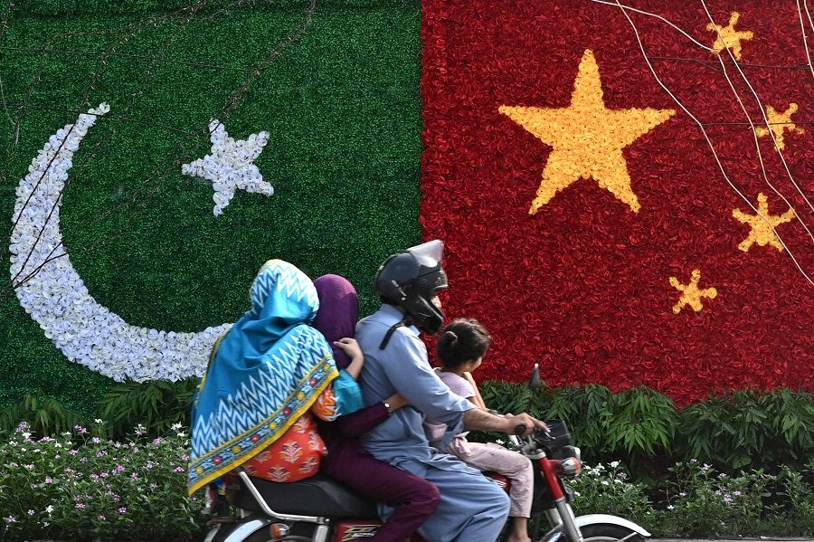 A family rides past a decoration in the shape of the national flags of China and Pakistan installed along a road ahead of the visit of Chinese Vice-Premier He Lifeng, in Lahore, Pakistan, on 30 July 2023. He Lifeng was due in the Pakistan capital on 30 July to mark the 10th anniversary of a mega economic plan that is the cornerstone of Beijing's Belt and Road Initiative. (Arif Ali/AFP)