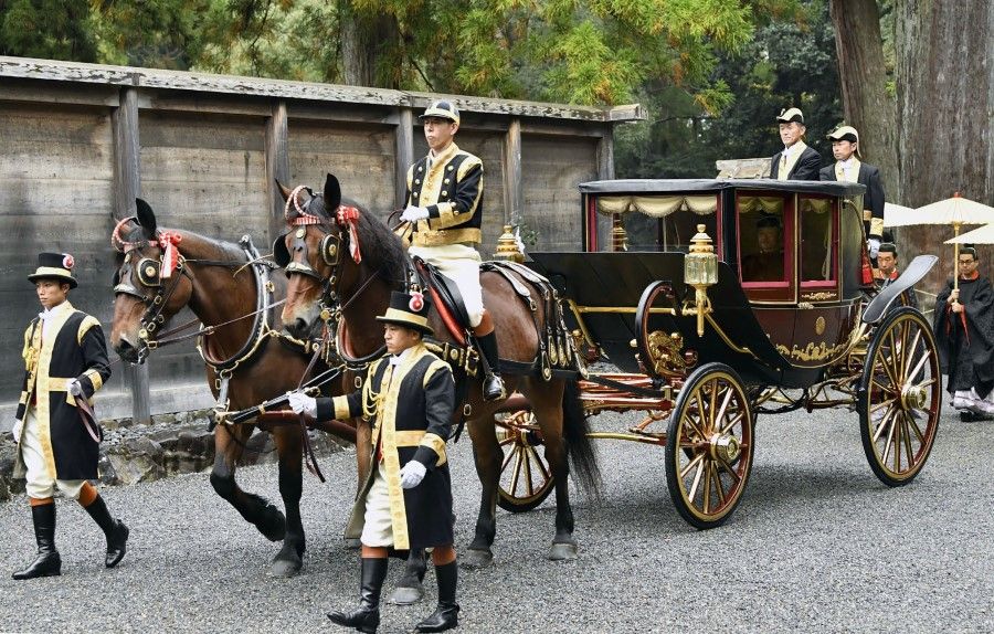Japan's Emperor Naruhito in traditional robes sits in a horse-drawn carriage following his enthronement. Palace staff are wearing Western-style clothes, while other participants in traditional black robes follow behind. (AFP)