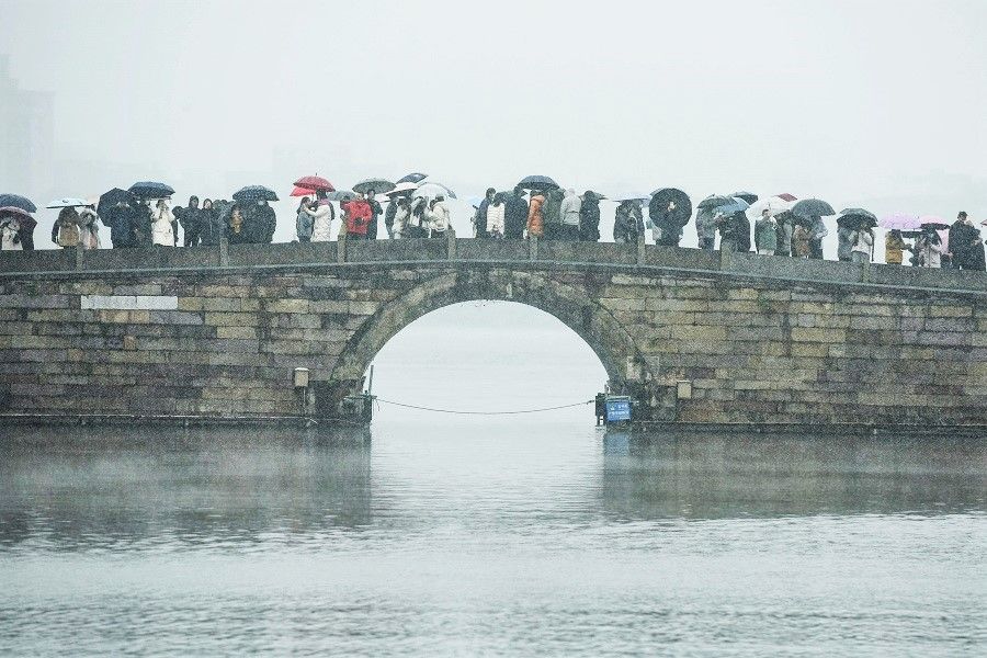 People visit West Lake during snowfall in Hangzhou, Zhejiang province, China, on 1 December 2022. (AFP)