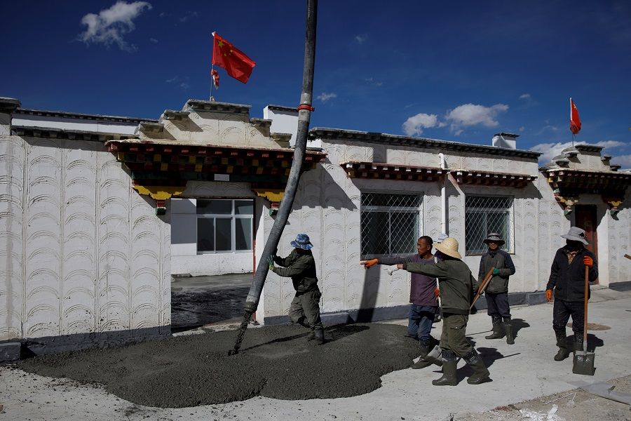 Workers pour concrete on a pavement in the village of Caiqutang, officially created as a relocation site for rheumathritis patients, Damxung county, during a government-organised tour of poverty alleviation efforts, Tibet Autonomous Region, China, 16 October 2020. (Thomas Peter/Reuters)