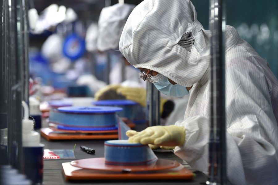Workers produce adhesive tapes for flexible printed circuits (FPC) at a factory in Yancheng, Jiangsu province, China, on 15 September 2021. (STR/AFP)