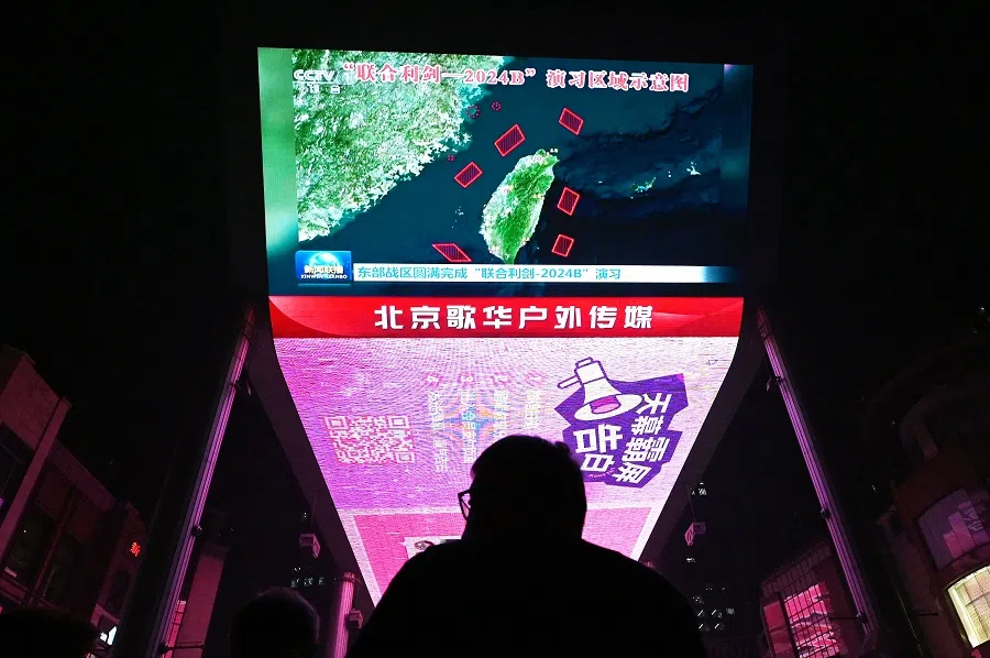 A man watches a news programme about Chinese military drills surrounding Taiwan, on a giant screen outside a shopping mall in Beijing, China, on 14 October 2024. (Greg Baker/AFP)