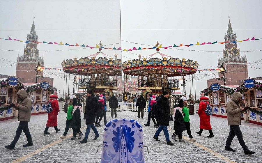 People walk on Red Square in front of a merry-go-round and the Kremlin's Spasskaya Tower in central Moscow, Russia, on 24 February 2023. (Yuri Kadobnov/AFP)