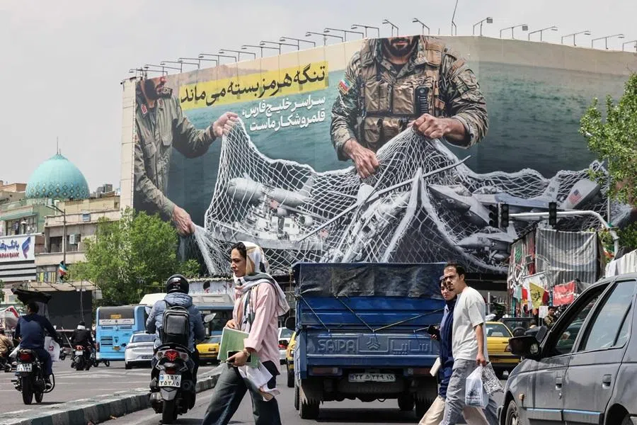 Iranian walks past a giant billboard reading “The Strait of Hormuz remains closed” at the Revolution Square in Tehran on 22 April 2026. (Atta Kenare/AFP)