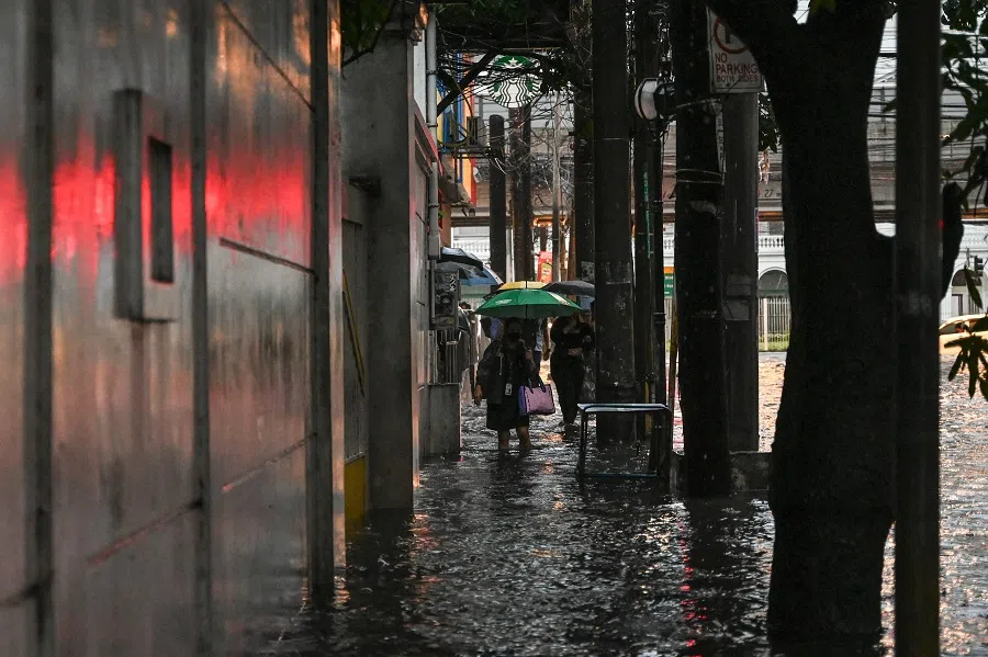 People walk along a flooded street in Manila, Philippines on 24 July 2024.