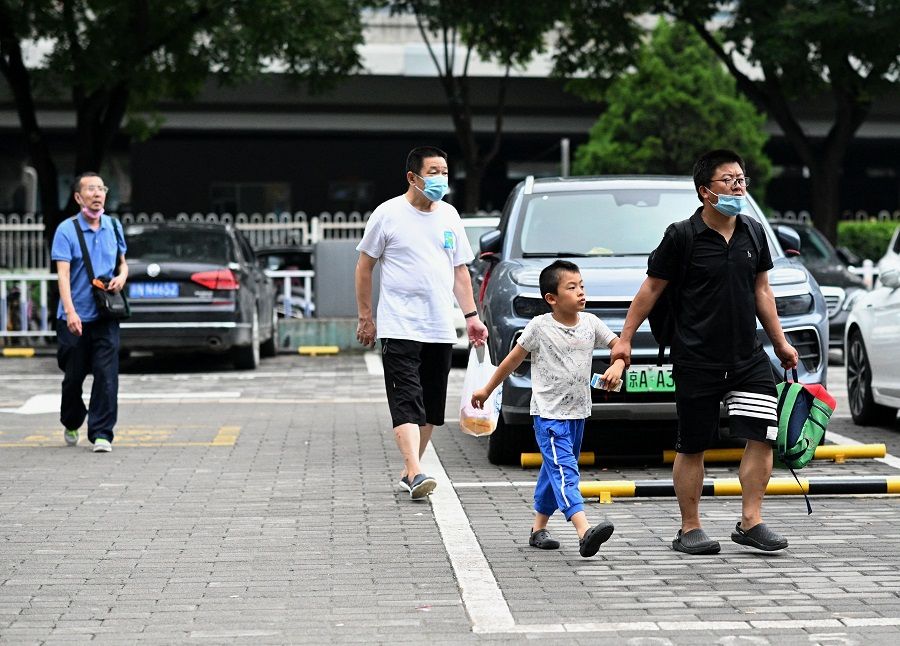 This picture taken on 28 July 2021, shows a student walking with his parent arriving to attend a private after-school education class in Haidian district, Beijing, China. Houses in Beijing's Haidian district go for millions as parents compete for a spot in top schools for their children in the elite school district. (Noel Celis/AFP)