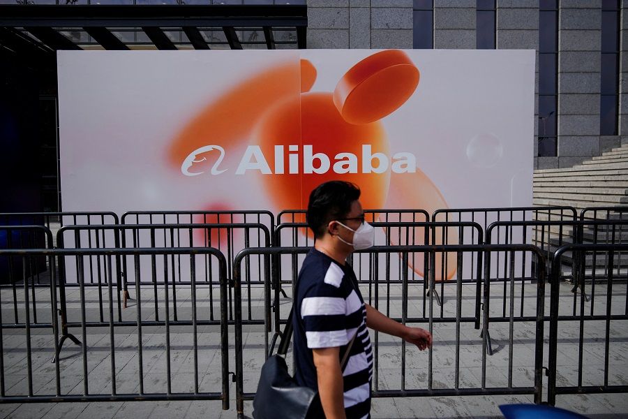 A person walks past a sign of Alibaba Group during the World Artificial Intelligence Conference in Shanghai, China, 1 September 2022. (Aly Song/Reuters)