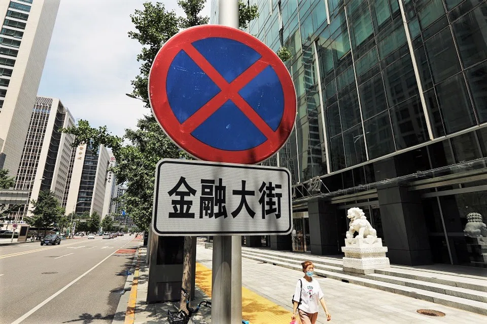 A woman walks past a sign of the Financial Street in Beijing, China, 9 July 2021. (Tingshu Wang/Reuters)