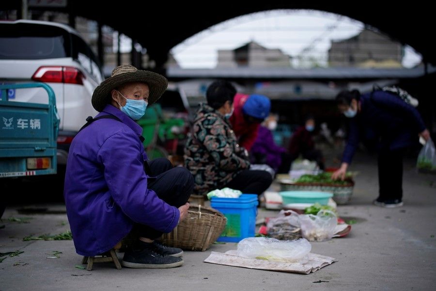 Street vendors wait for customers at their vegetable stalls in Jingzhou, 27 March 2020. (Aly Song/REUTERS)