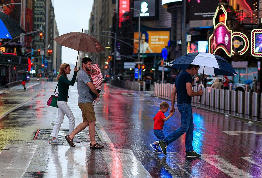 People cross the street as rain falls in Times Square, in New York, US, on 22 August 2021. (Kena Betancur/AFP)