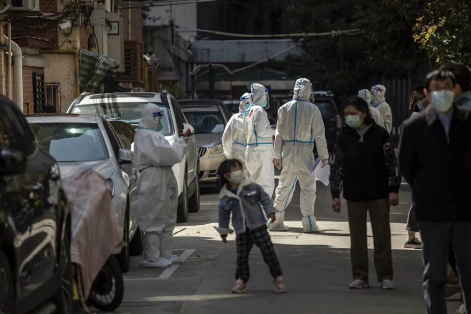 Workers in personal protective equipment (PPE) keep watch as residents queue for a Covid-19 test in a neighbourhood placed under lockdown in Shanghai, China, on 4 April 2022. (Qilai Shen/Bloomberg)