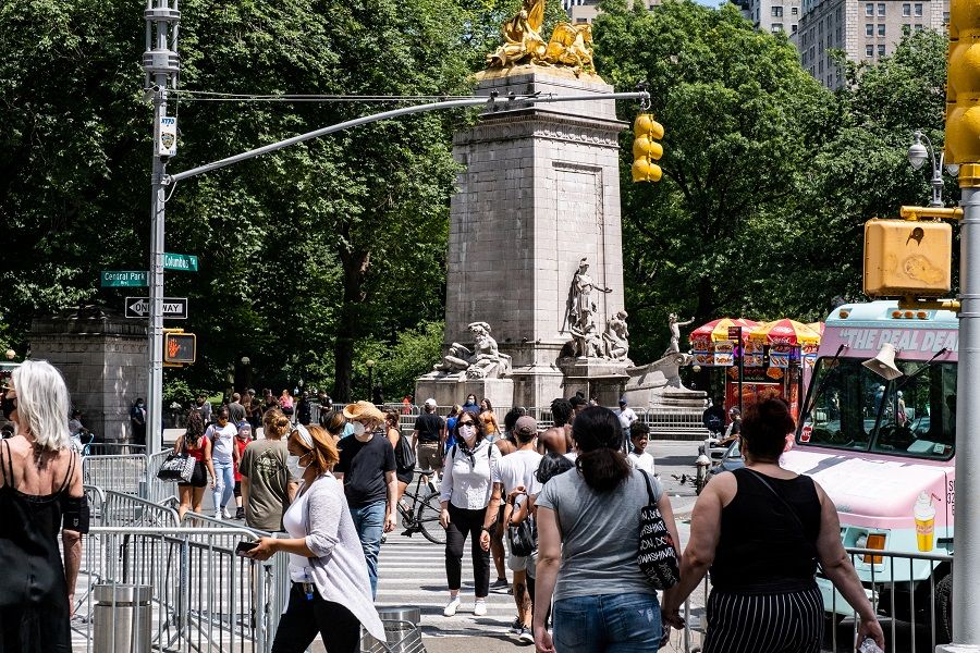 People wearing face masks enjoy the weather near Central Park, in the Manhattan borough of New York City, US, on 21 June 2020. (Jeenah Moon/Reuters)