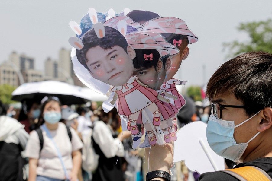 This file photo taken on 3 May 2021 shows a fan holding images of actors as fans wait outside the Suzhou Olympic Sports Centre Stadium before a concert with the theme of the Chinese television drama 'Word of Honor', in Suzhou in China's eastern Jiangsu province. From reality TV to online gaming and even pop stans, China's leadership has launched a crackdown on youth culture in what experts say is a bid to ramp up "ideological control". (STR/AFP)