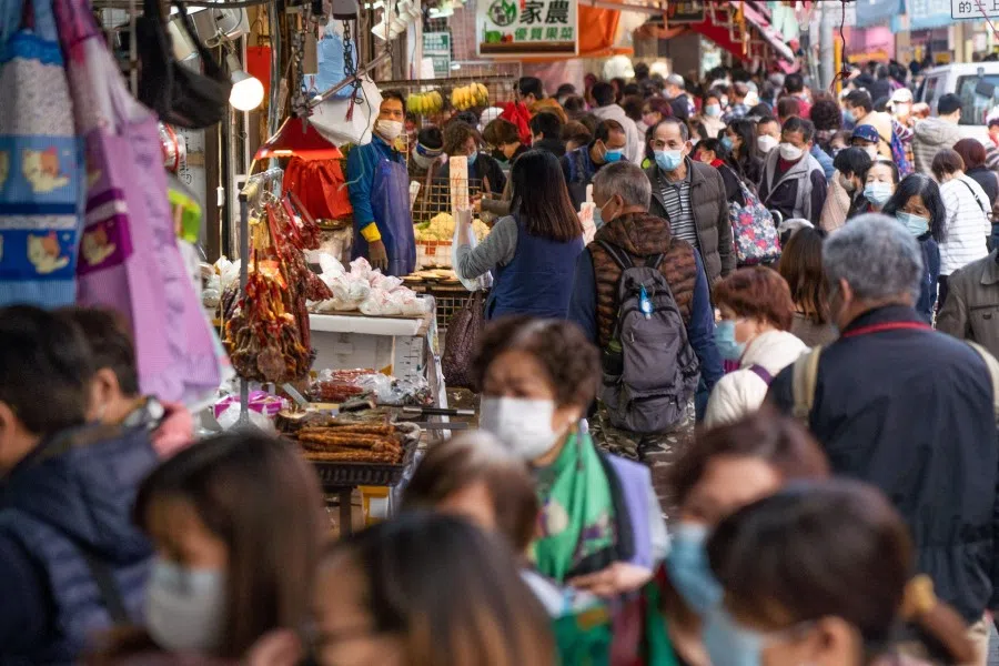 People walk past a wet market in Hong Kong's Kwun Tong area on 26 February 2022, as authorities announced a record number of new infections. (Bertha Wang/AFP)
