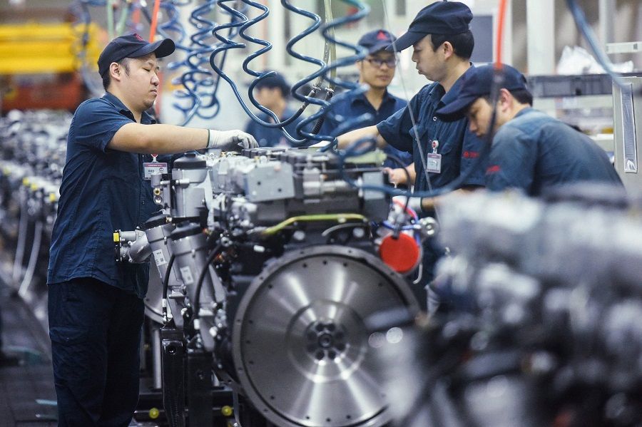 This file photo taken on 18 October 2021 shows workers producing heavy truck engines at a factory in Hangzhou, Zhejiang province, China. (AFP)