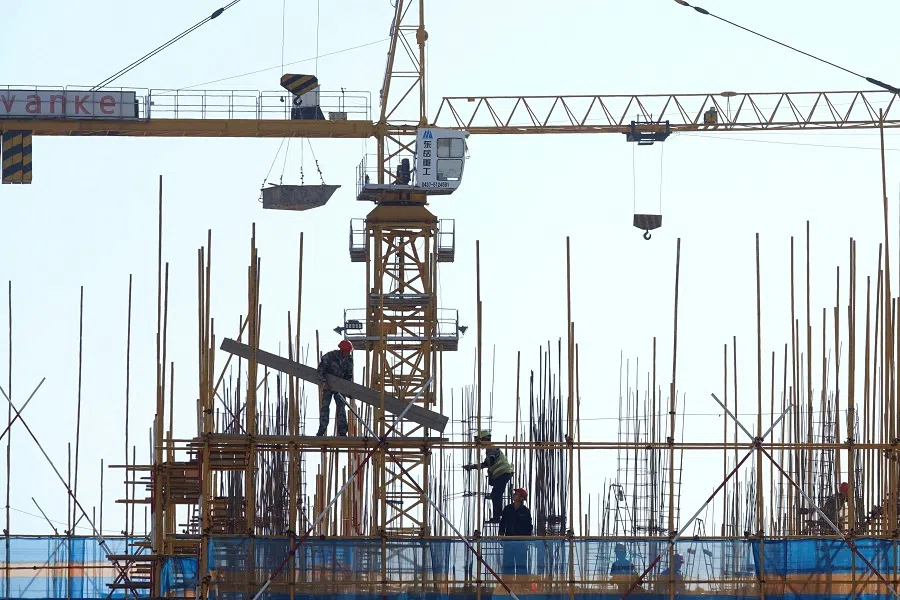 A Vanke sign is seen above workers working at the construction site of a residential building in Dalian, Liaoning province, China, on 16 September 2019. (Stringer/Reuters)